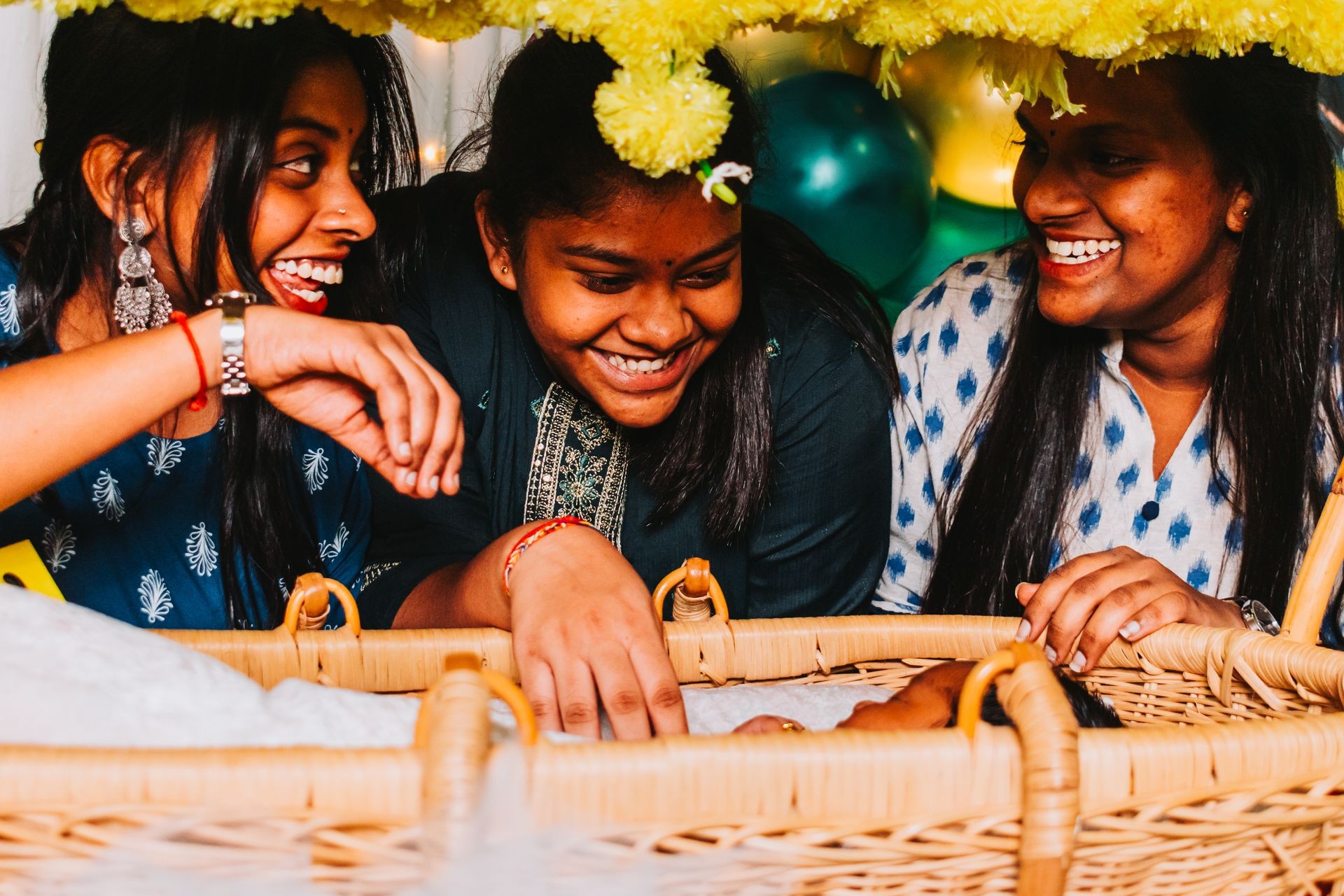 A group of people looking at a baby in a wicker basket adorned with yellow flowers.